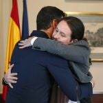 El presidente del Gobierno español en funciones, el socialista Pedro Sánchez (i), y el líder de Unidas Podemos, Pablo Iglesias, se abrazan en el Congreso tras firmar un acuerdo para la formación de un Ejecutivo, el 12 de noviembre