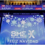 Vista del principal indicador de la Bolsa española, el IBEX 35 y un cartel de felicitación navideña en Madrid este jueves