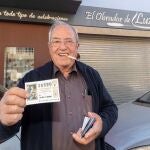 Uno de los agraciados con el gordo de la lotería de navidad, Santiago Palazón, muestra el décimo premiado junto al obrador donde lo compró. EFE/Marcial Guillén