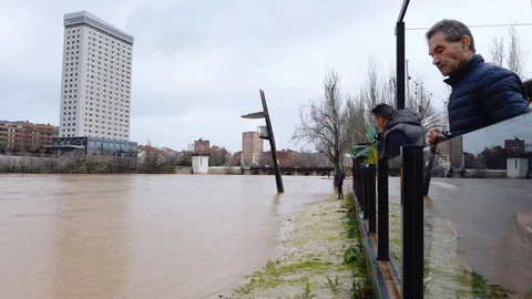 GRAF3411. VALLADOLID, 22/12/2019.- El temporal que azota los últimos días la península ibérica afecta este domingo a Castilla y León con rachas de viento de hasta 100 kilómetros por hora, así como con inundaciones en algunas carreteras a causa de las crecidas de los ríos de la Cuenca del Duero. En la imagen, Varias personas observan el caudal del Pisuerga a su paso por la ciudad de Valladolid, que ha superado el nivel de alarma. EFE/NACHO GALLEGO