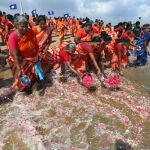 Un grupo de mujeres arroja flores en la costa en recuerdo de las víctimas del tsunami de 2004