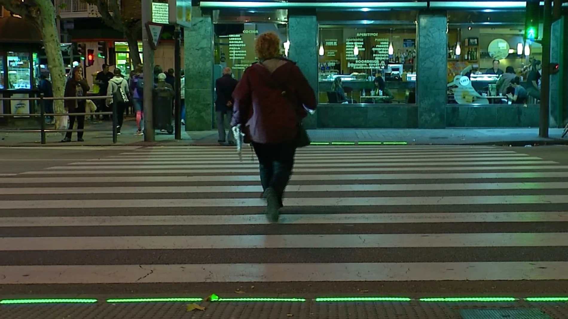 Una salmantina pasa por un cruce iluminado para indicar al peatón despistado con el móvil si debe cruzar o no