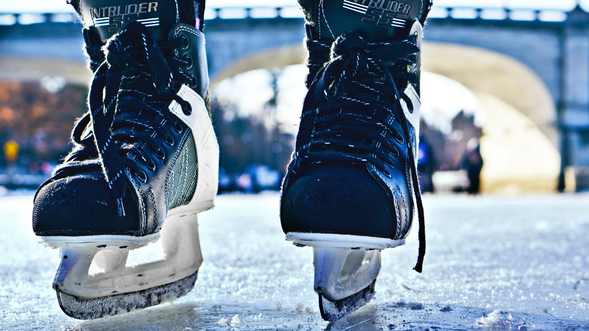 Fotografía de cerca de un par de patines sobre el hielo, acercándose hacia el observador.