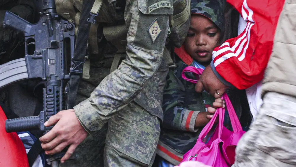 Una niña acompañada de militares durante la evacuación