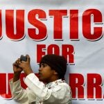 Un niño se apoya en un letrero mientras filma a los partidarios de Pervez Musharraf, luego de que un tribunal paquistaní condenó a muerte al ex gobernante militar por cargos de alta traición y subvirtiendo la constitución, durante una protesta en Karachi, Pakistán, el 20 de diciembre de 2019.