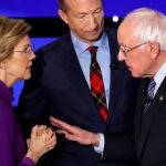 La senadora Elizabeth Warren habla con el senador Bernie Sanders, ante la atenta mirada del millonario Tom Steyer