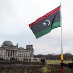 Una mujer ondea una bandera de Libia delante del Reichstag durante la cumbre de Berlín. EFE/EPA/HAYOUNG JEON