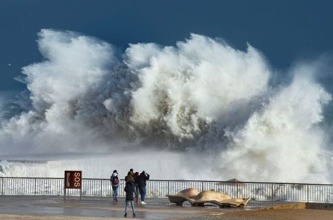 Varias personas observan las grandes olas en la playa de la Barceloneta, en Barcelona, este lunes, durante el fuerte temporal de Levante que azota Cataluña y que deja registros históricos de oleaje, viento y nieve.