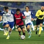 El delantero español del Real Zaragoza Javi Puado (i) disputa un balón con Take Kubo, centrocampista del CD Mallorca, durante el partido entre ambos equipos correspondiente a la tercera eliminatoria de la Copa del Rey, disputado este martes en el estadio de la Romareda, en Zaragoza