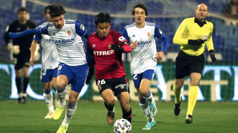 El delantero español del Real Zaragoza Javi Puado (i) disputa un balón con Take Kubo, centrocampista del CD Mallorca, durante el partido entre ambos equipos correspondiente a la tercera eliminatoria de la Copa del Rey, disputado este martes en el estadio de la Romareda, en Zaragoza