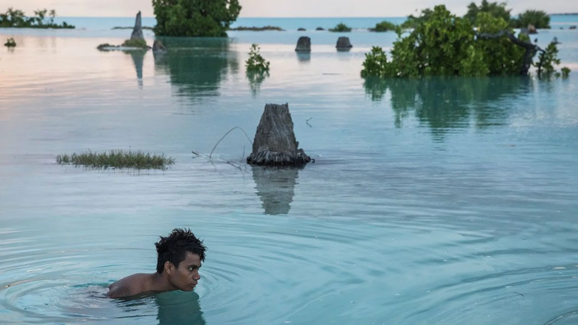 Un niño de 16 años nada en la zona inundada en Kiribati.