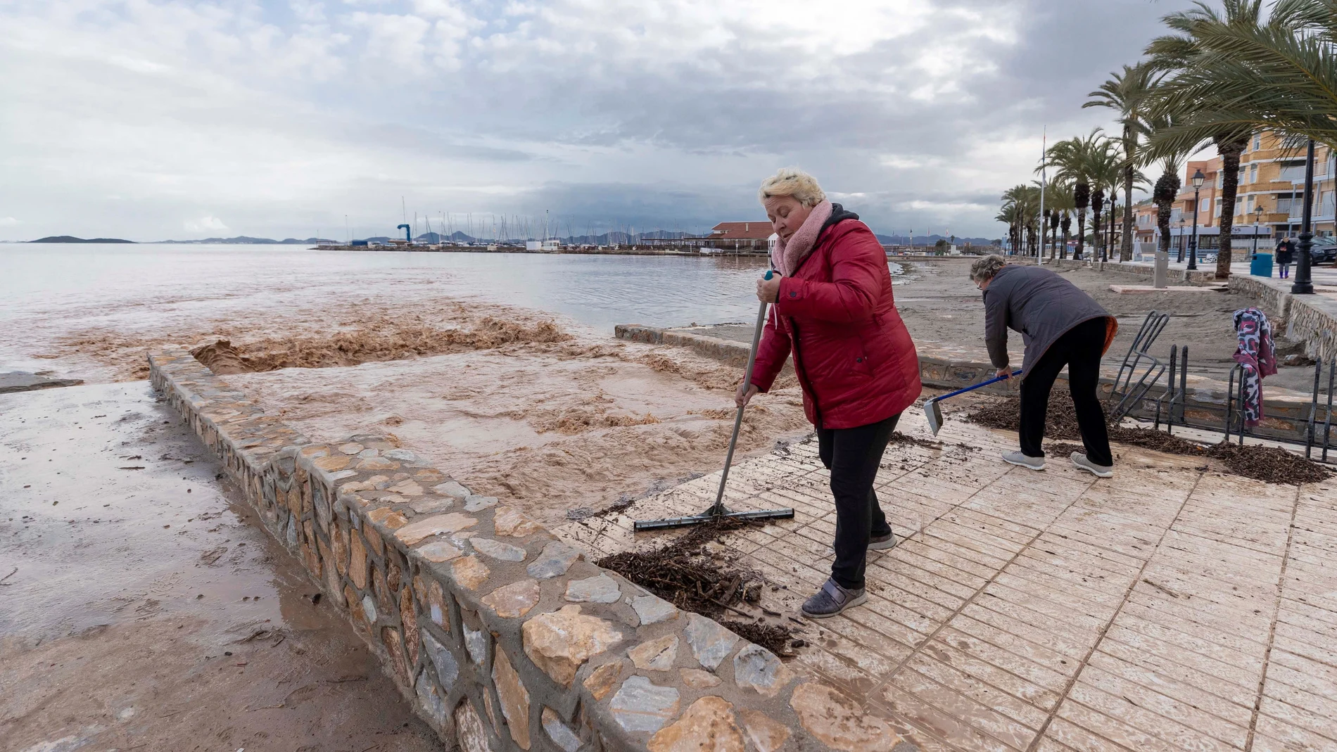 Dos vecinas de Los Alcázares retiran restos de arbustos de las aguas de lluvia que estan entrando en el Mar Menor, tras las intensas lluvias de septiembre. Imagen de Archivo