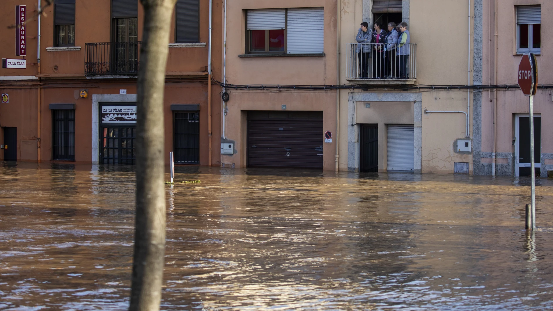 People stand at a balcony during flooding following a storm in Girona, Spain, on Thursday, Jan. 23, 2020. At least 11 have died and five people remained missing on Thursday following a calamitous storm that has caused rivers to overflow and sea waters to inundate vast agricultural areas in eastern Spain. (AP Photo/Emilio Morenatti)