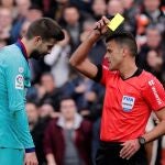 El defensor Gerard Piqué (i) del Barcelona, es amonestado con tarjeta amarilla por el árbitro central Jesús Gil tras una falta sobre el defensor José Luis Gayá del Valencia, durante el partido correspondiente a la vigésimo primera jornada de LaLiga Santander que se disputa este sábado en el estadio de Mestalla