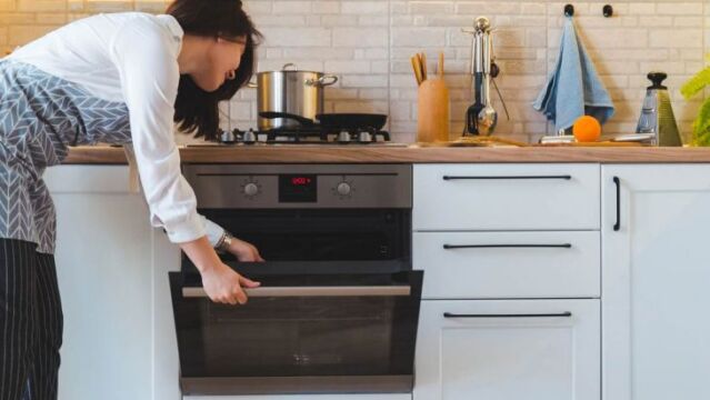 Una mujer hace uso del horno en su vivienda