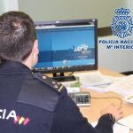 Un policía nacional investiga delante de un ordenador