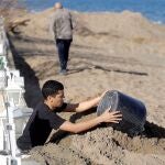 Un hombre retira los cerca de dos metros de arena que el temporal Gloria ha acumulado ante su vivienda de Dénia