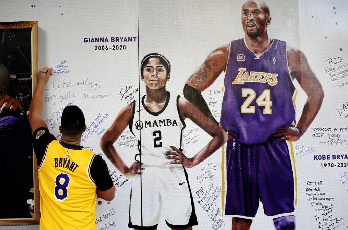 Jesse Reyes Zaragoza writes a message on a memorial display of Kobe Bryant and his daughter, Gianna, outside the Golden 1 Center before the Lakers played the Sacramento Kings in an NBA basketball game in Sacramento, Calif., Saturday, Feb. 1, 2020. (AP Photo/Rich Pedroncelli)