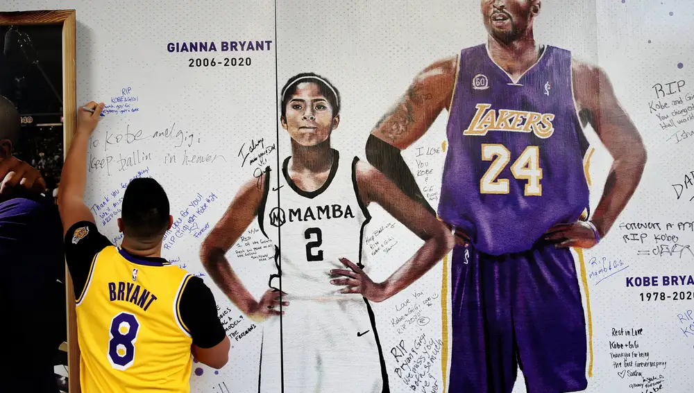 Jesse Reyes Zaragoza writes a message on a memorial display of Kobe Bryant and his daughter, Gianna, outside the Golden 1 Center before the Lakers played the Sacramento Kings in an NBA basketball game in Sacramento, Calif., Saturday, Feb. 1, 2020. (AP Photo/Rich Pedroncelli)