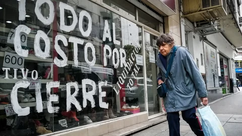 Una mujer pasa frente a una vitrina que anuncia su liquidación por cierre
