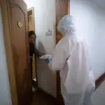 Un sanitario entrega un pack de comida a una paciente en cuarentena