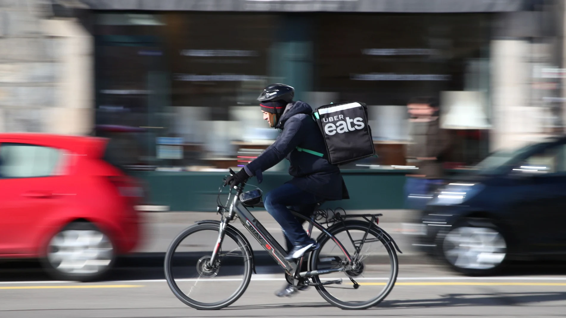 An Uber Eats food delivery courier rides an electric bike in Geneva