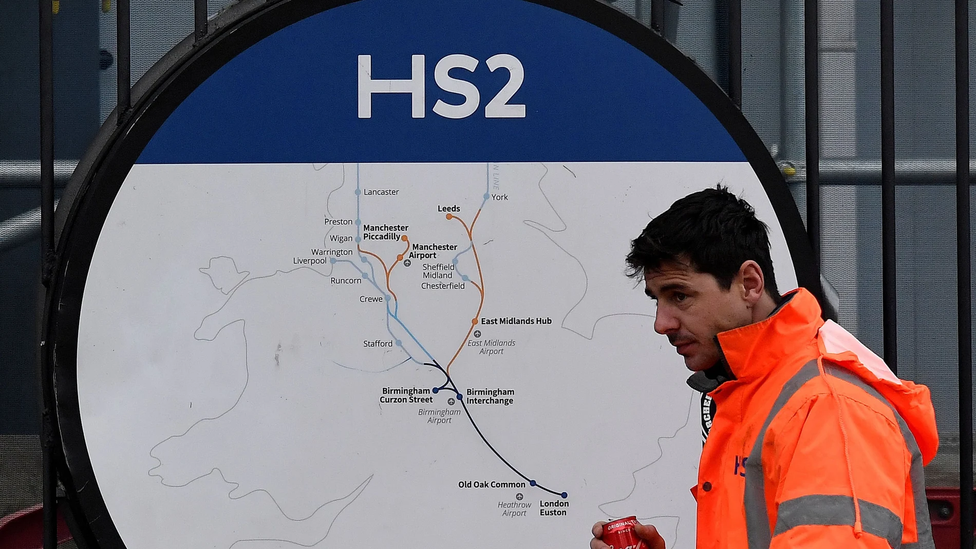 FILE PHOTO: An HS2 worker walks past signage on perimeter fencing at the HS2 high speed rail link construction site in Euston, London
