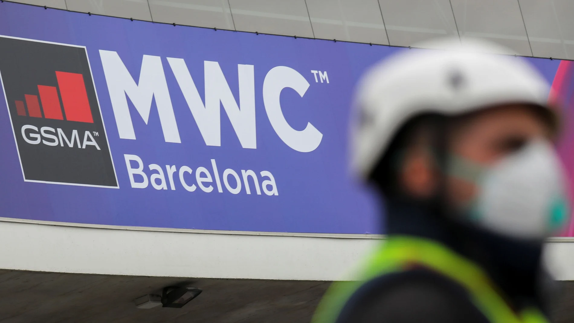 Employee is pictured next to the logo of MWC20 (Mobile World Congress) in Barcelona