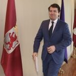 El presidente Fernández Mañueco pasa por delante de la bandera de León antes de entrar al hemiciclo