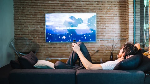 Un hombre viendo la televisión en el salón de su casa