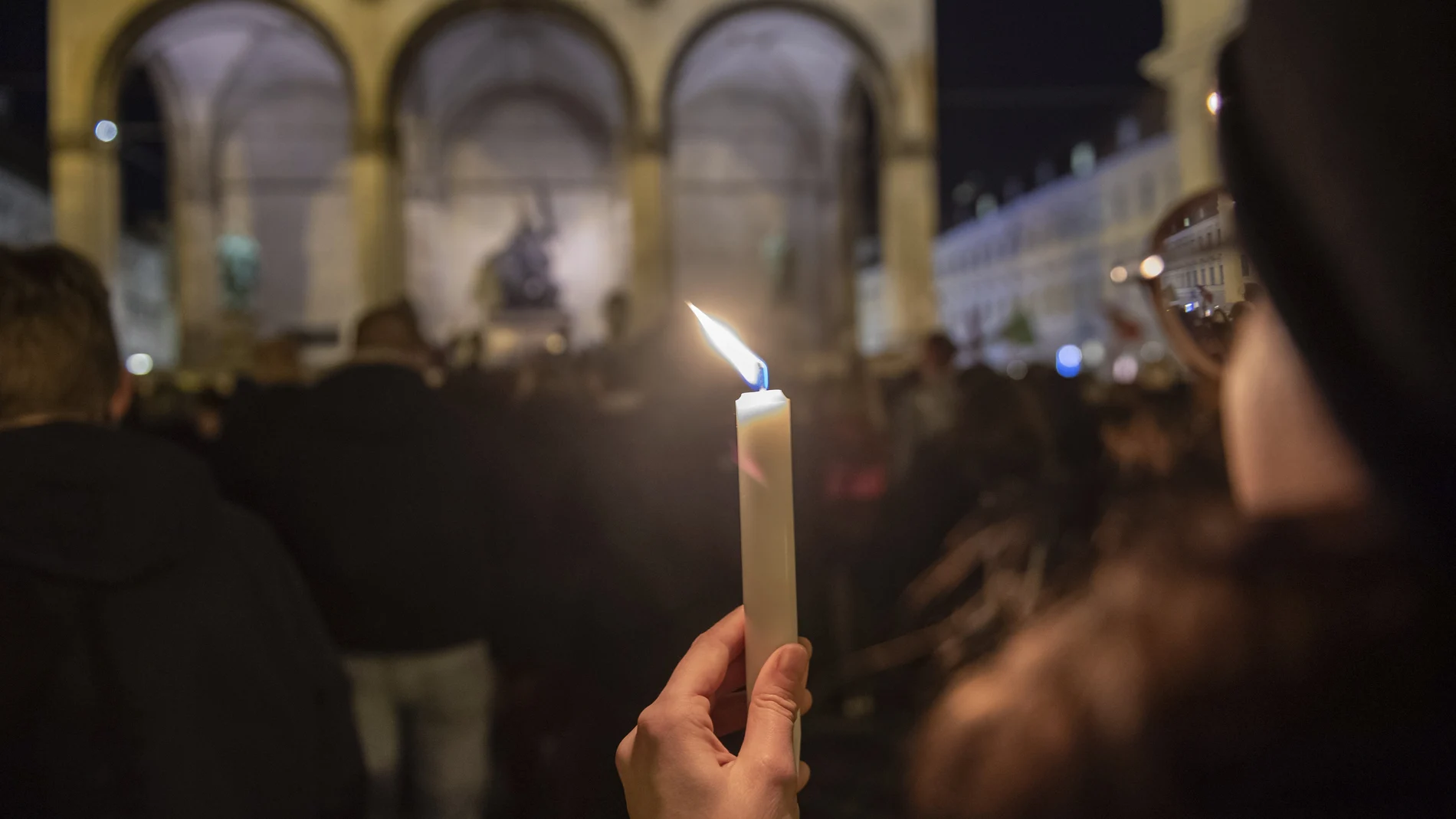 Una mujer con una vela en la vigilia en el centro de Munich