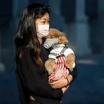 Una mujer y su mascota con mascarillas en la ciudad china de Guangzhou. EFE/EPA/ALEX PLAVEVSKI