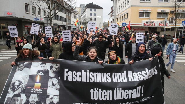 La gente sostiene una pancarta que dice "¡El fascismo y el racismo matan en todas partes!" Mientras marchan por una protesta contra el ataque terrorista racista en Hanau, Alemania, el 22 de febrero de 2020