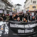 La gente sostiene una pancarta que dice "¡El fascismo y el racismo matan en todas partes!" Mientras marchan por una protesta contra el ataque terrorista racista en Hanau, Alemania, el 22 de febrero de 2020