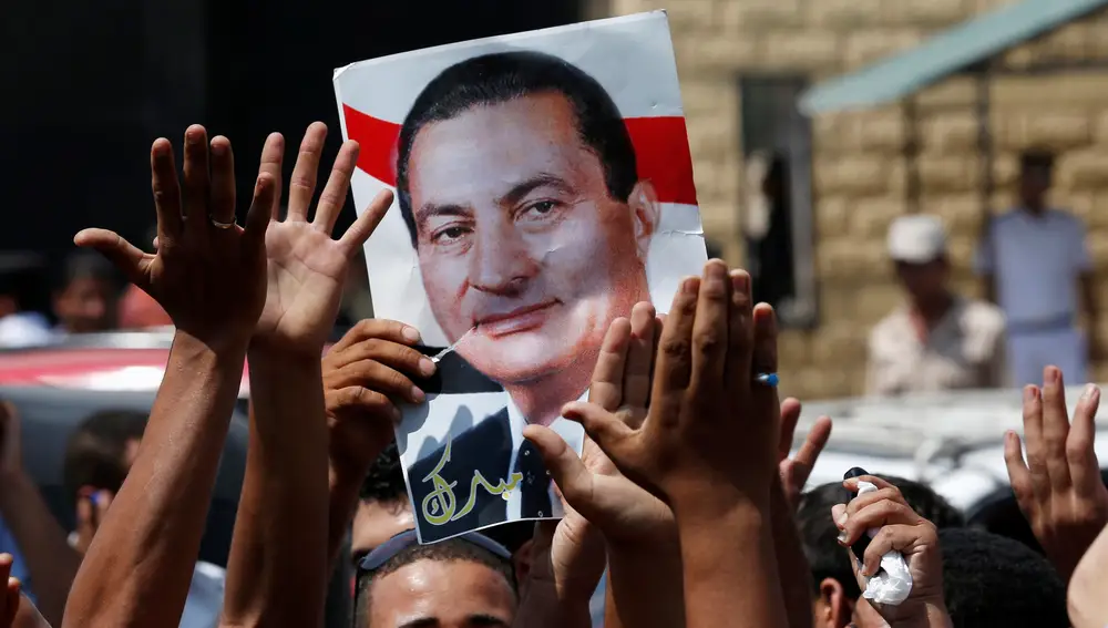FILE PHOTO: Supporters of former president Hosni Mubarak hold his poster to celebrate his release in front of the main gate of Tora prison, on the outskirts of Cairo August 22, 2013. REUTERS/Youssef Boudlal/File Photo