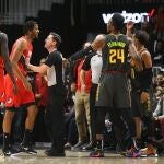 Un árbitro sujeta a Trevor Ariza después del codazo que propinó a Trae Young