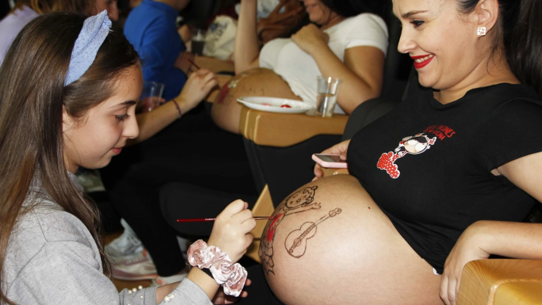 Una de las embarazadas se deja pintar el vientre por una niña en el Hospital Vinalopó, de Ribera Salud