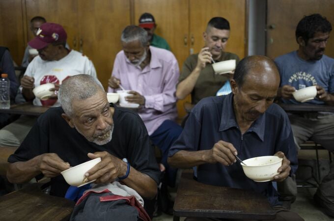 Un grupo de venezolanos comen arroz y lentejas en un centro social en Caracas (AP Photo/Ariana Cubillos)