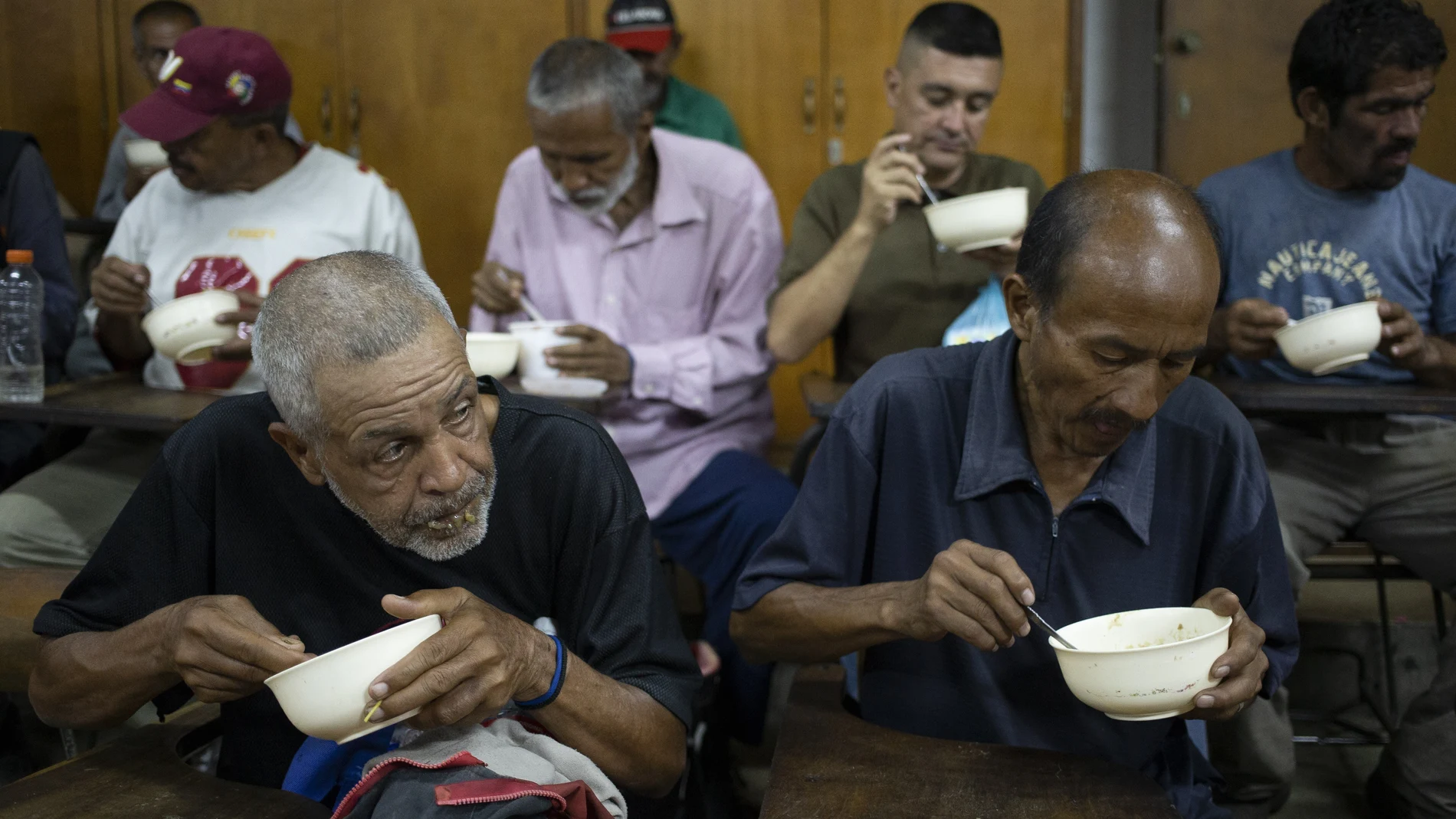 Un grupo de venezolanos comen arroz y lentejas en un centro social en Caracas (AP Photo/Ariana Cubillos)