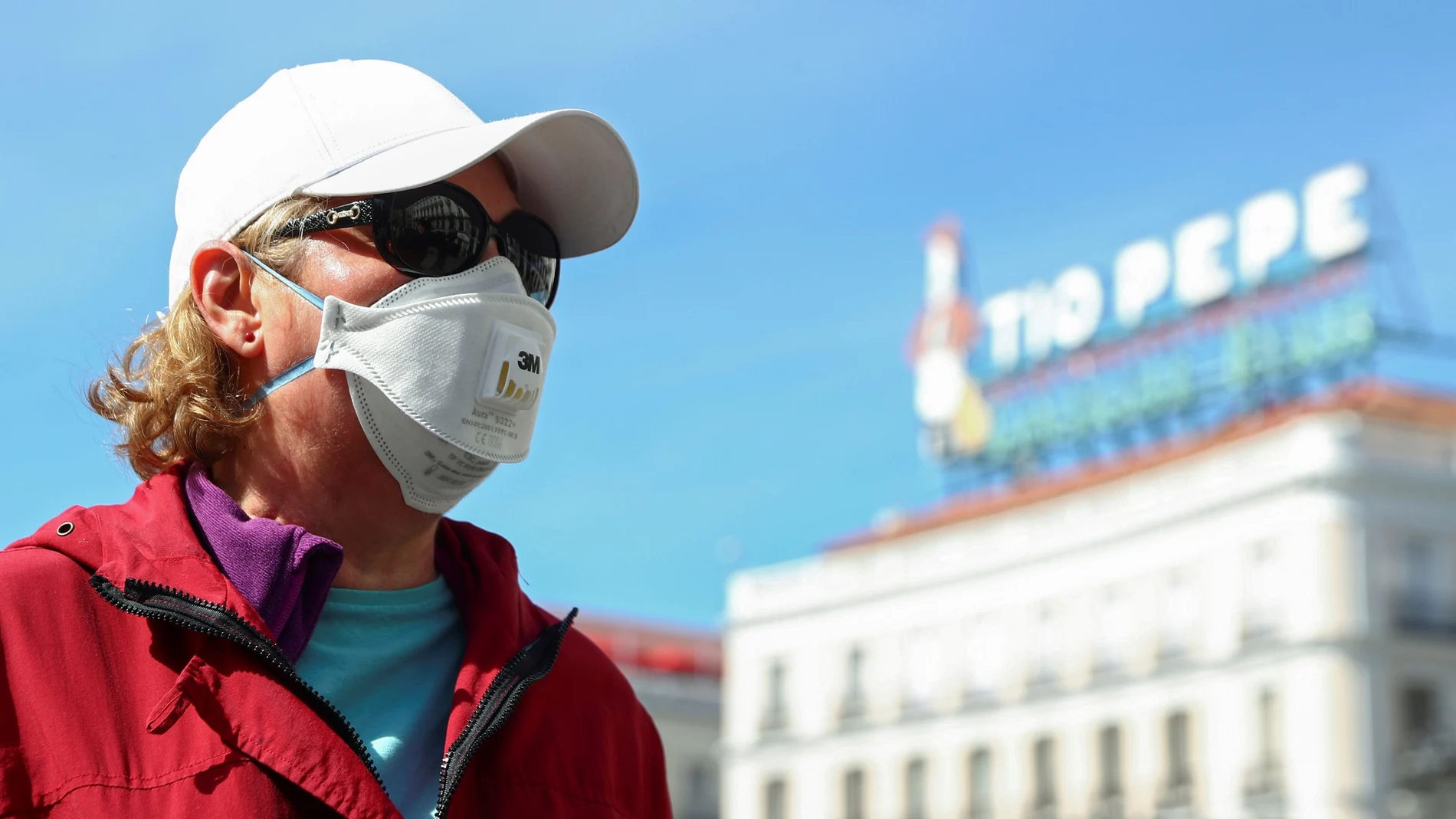 A woman wears a protective face mask as she stands at one of the main touristic landmarks Puerta del Sol in Madrid
