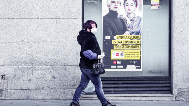 Una mujer de rasgos asiáticos pasea con una mascarilla por una calle de Madrid tras el incremento de casos de coronavirus en la Comunidad de Madrid