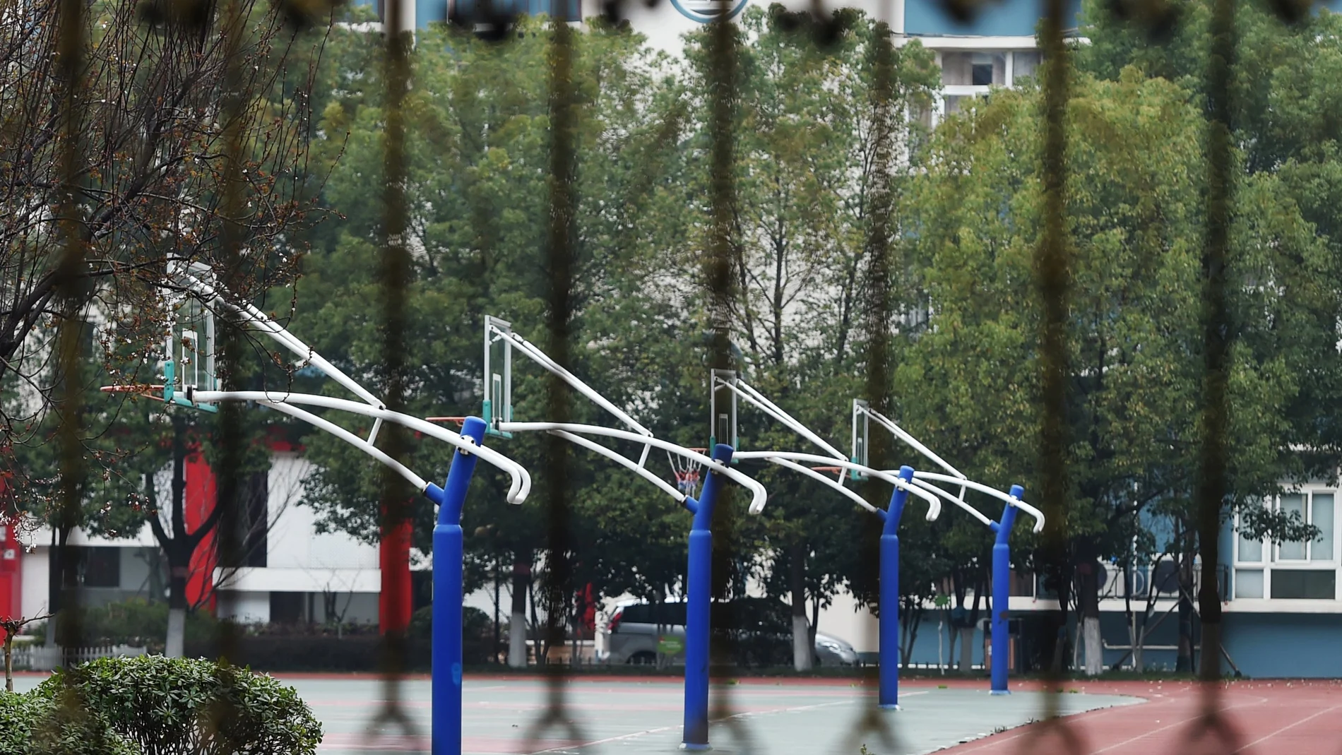 Basketball courts are seen behind the fence of a closed secondary school in Wuhan, the epicentre of the novel coronavirus outbreak