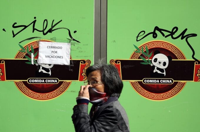 Una mujer con mascarilla pasa ante una tienda regentada por ciudadanos chinos en pleno centro de València