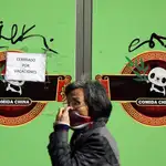 Una mujer con mascarilla pasa ante una tienda regentada por ciudadanos chinos en pleno centro de València
