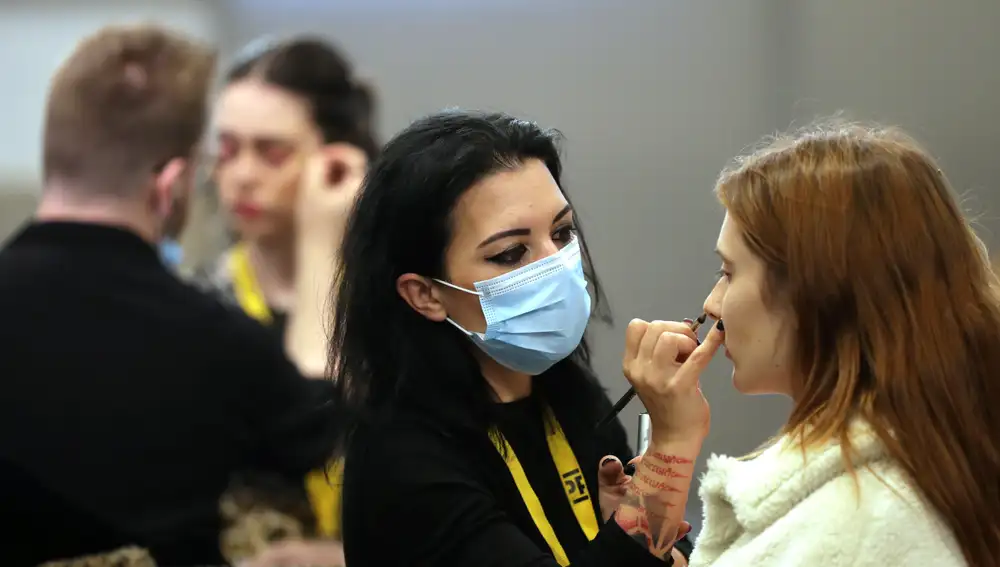 Una maquilladora maquilla a una modelo haciendo uso de su mascarilla