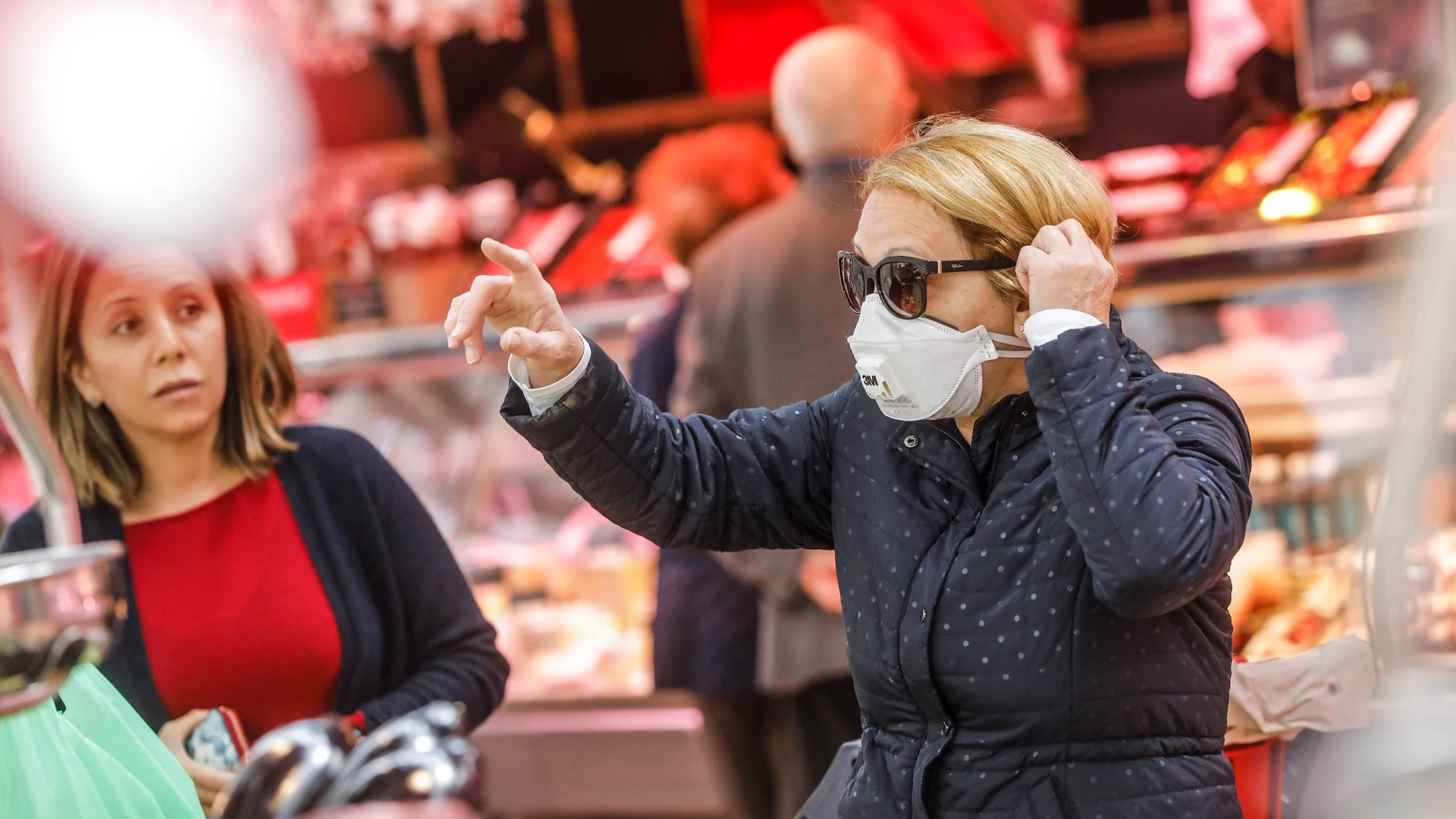 Una mujer en el Mercado Central de Valencia se protege con mascarilla del contagio por coronavirus