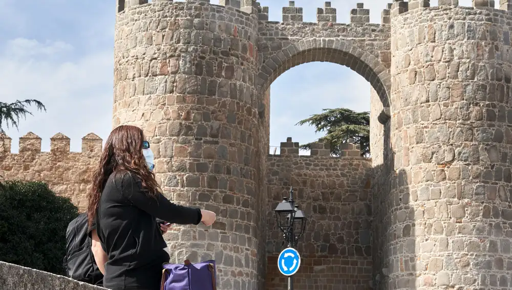 Una turista con mascarilla junto a la muralla de Ávila. EFE/ Raúl Sanchidrián