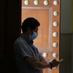 Un hombre observa su teéfono con una mascarilla para protegerse frente al coronavirus