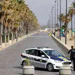 Un coche de la Policía Local de Valencia patrulla el paseo marítimo, conminando las personas a que regresen a casa, tras haber decretado el Gobierno el estado de alarma y el deber de confinamiento de los ciudadanos debido a la pandemia provocada por el Coronavirus.