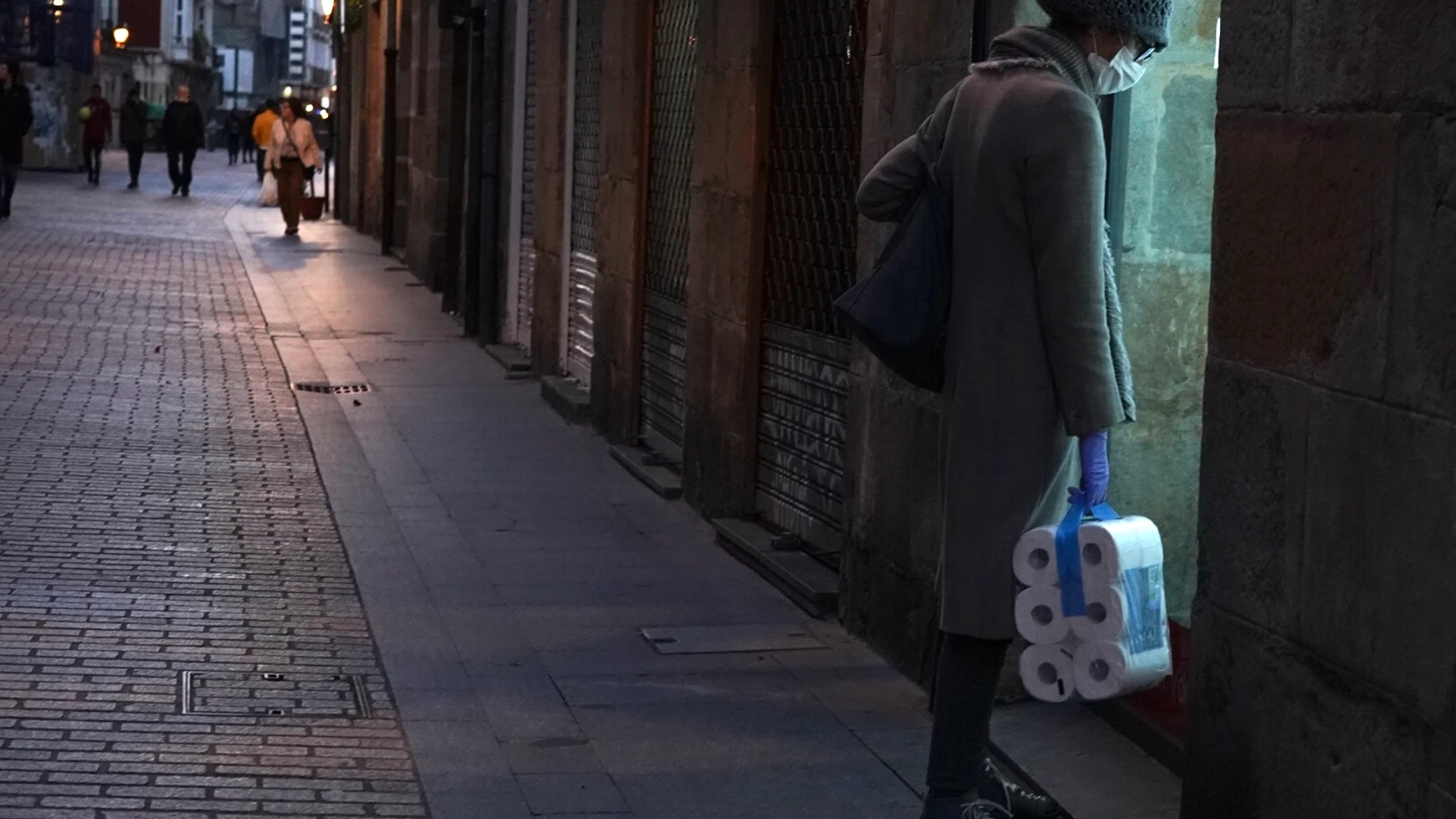 Transeúntes pasen por Bilbao tras la declaración de Estado de Alarma por coronavirus